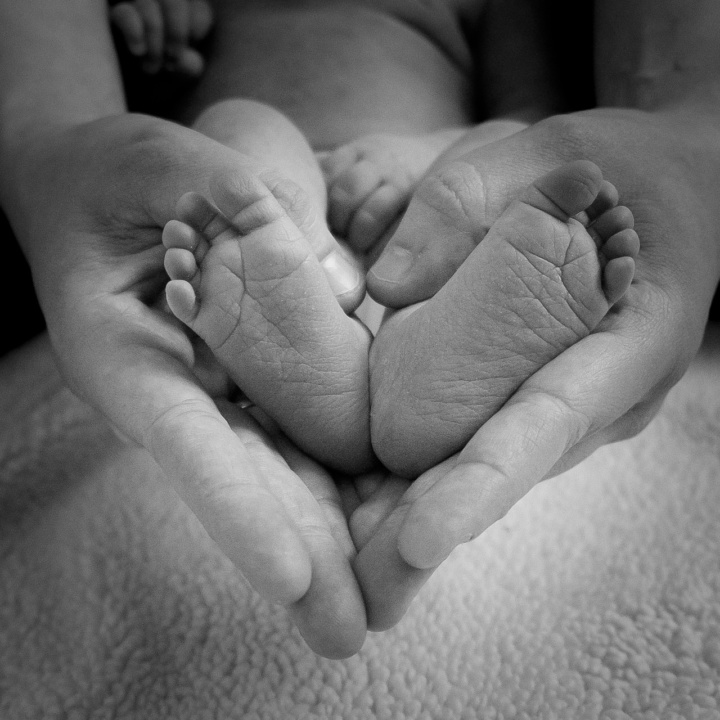 Vauvan jalkapohjat ja aikuisen kädet piirtävät sydämen